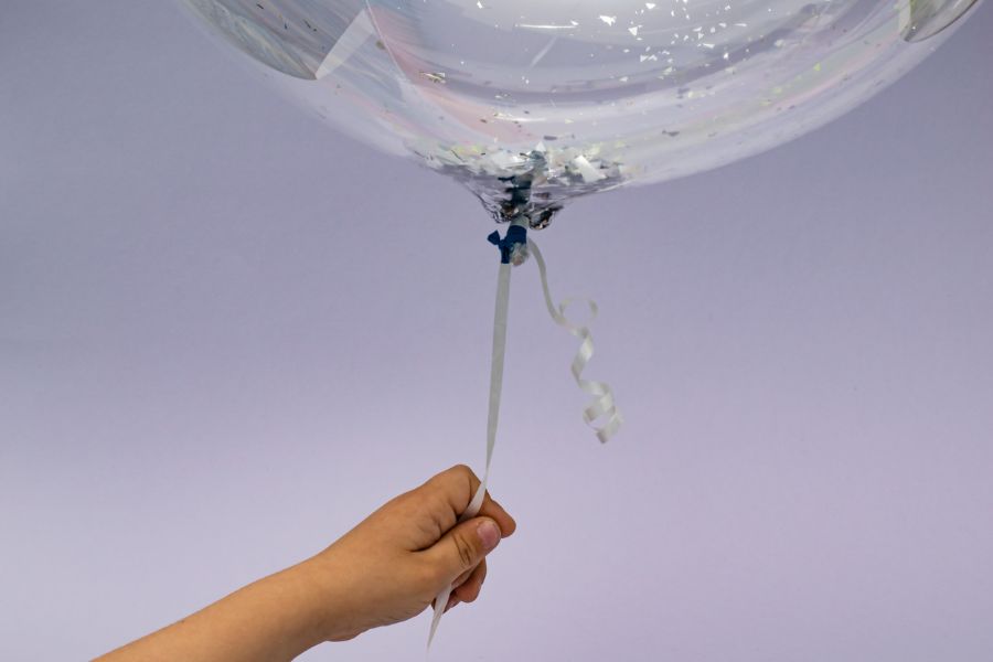 Hält einen mit Helium gefüllten Ballon